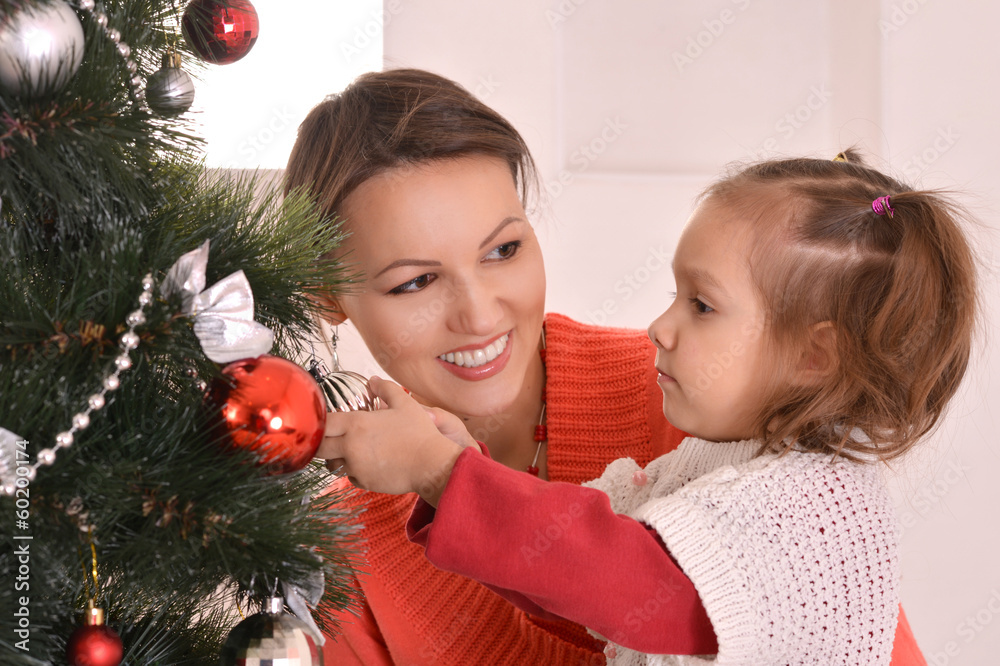 mother decorating christmas tree with daughter