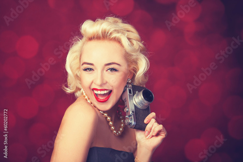 Beautiful blonde women with camera on red background.