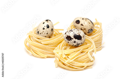 Italian pasta nests with quail eggs on it isolated on white photo