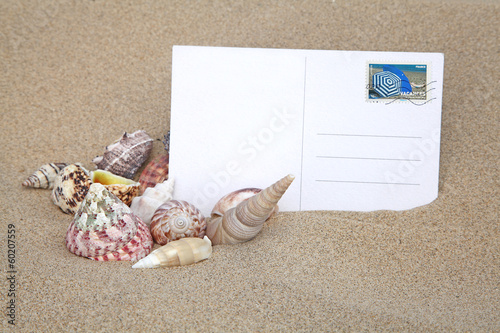 carte postale et coquillage sur le sable photo