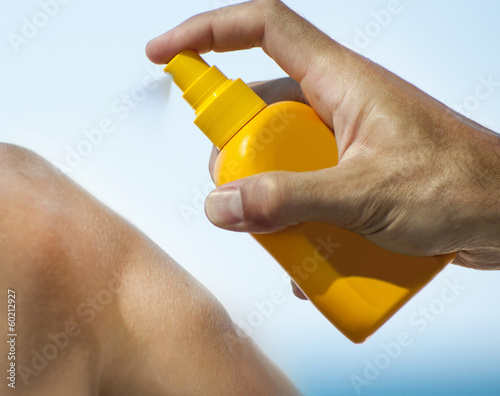 Man holding orange sun tan lotion