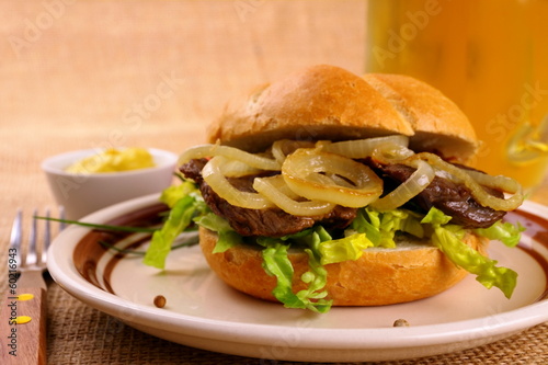 Grilled beef with onion rings in bun and beer photo