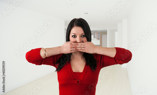 a young woman covers her mouth let alone in an empty room photo