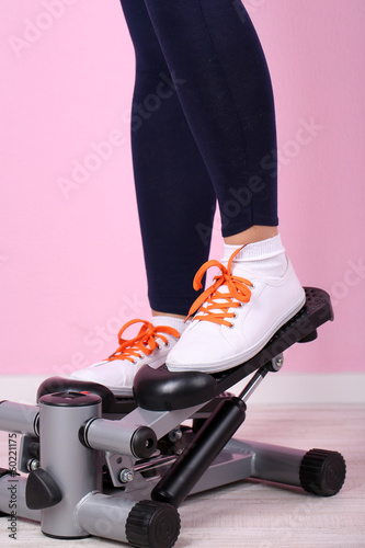 Woman doing exercise on stepper. Close-up on legs.