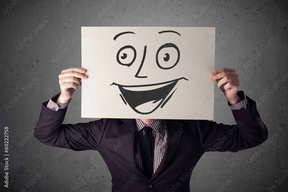 Businessman holding a cardboard with smiley face on it in front Businessman holding a cardboard with smiley face on it in front