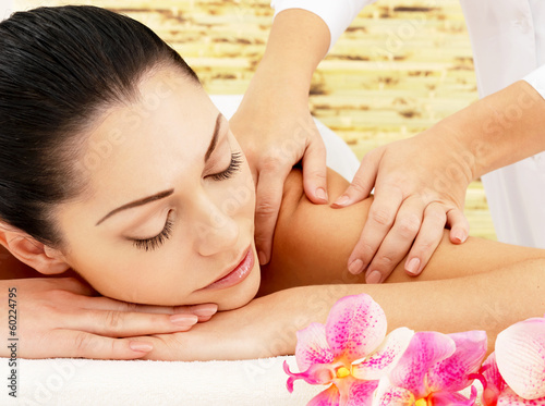 Woman having massage of shoulder in spa salon