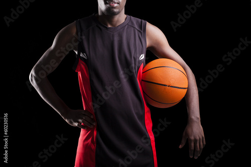 Image of a basketball player holding a ball against dark backgro © cristovao31
