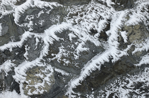 Snow and ice on a stone wall at winter