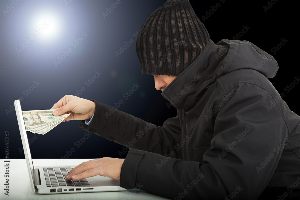 Computer hacker stealing money in the darkness Computer hacker stealing money in the darkness