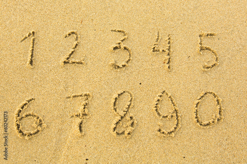 Numbers from one to ten written on a sandy beach.