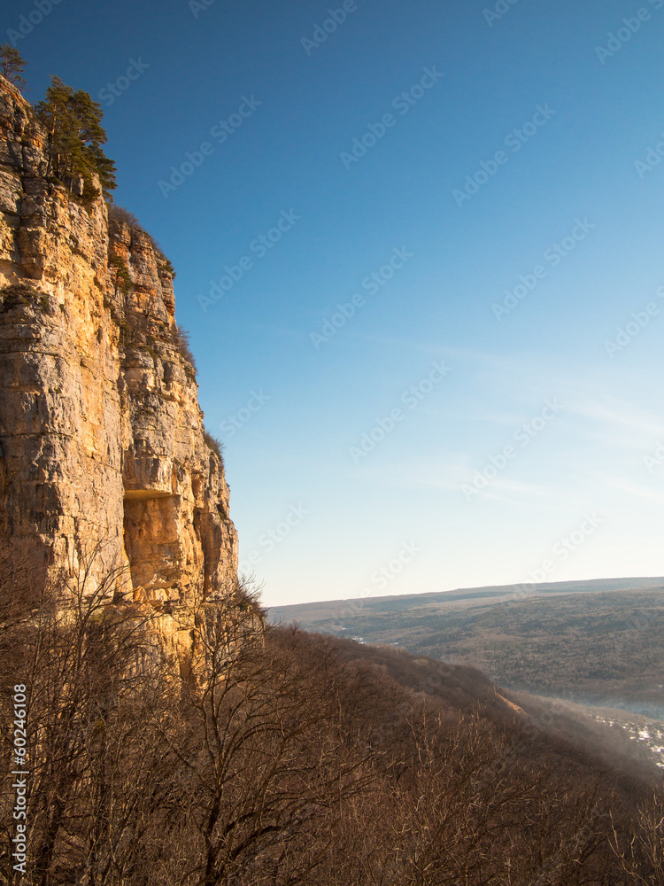 Sheer cliffs to the forest on the sky background