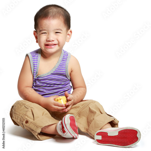 Smiling little asian boy sitting on floor