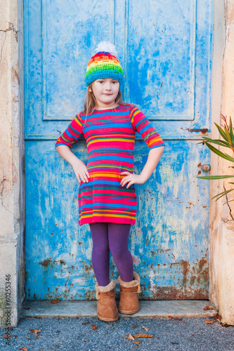Beautiful little girl in a colorful dress posing outdoors