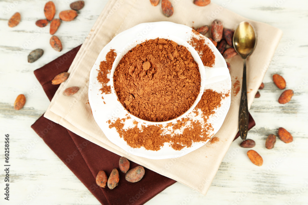 Cocoa powder in cup on napkin on wooden table Cocoa powder in cup on napkin on wooden table