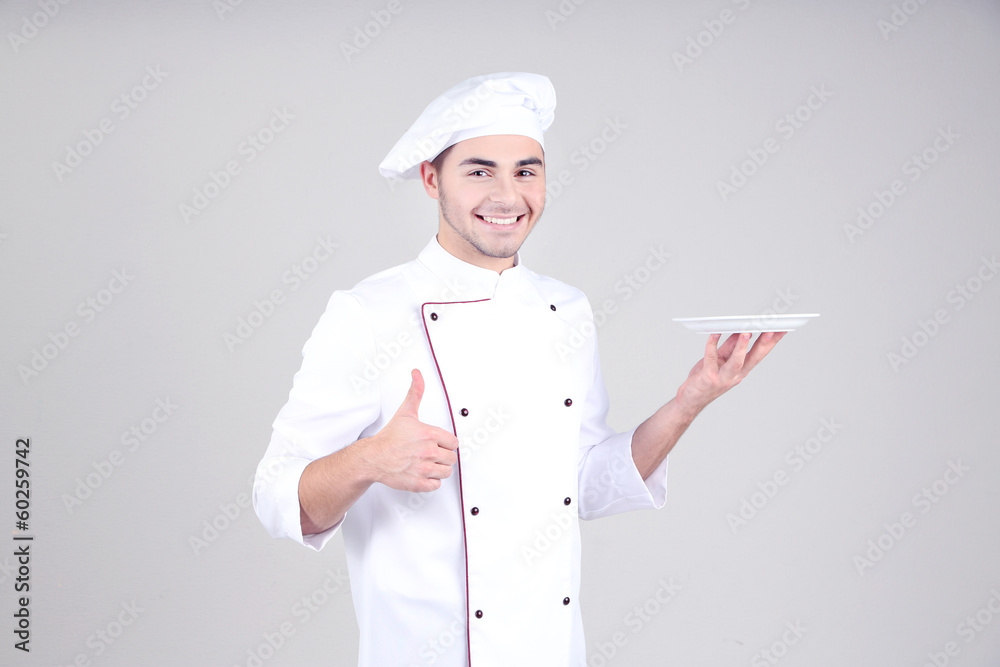 Professional chef in white uniform and hat, on gray background Professional chef in white uniform and hat, on gray background