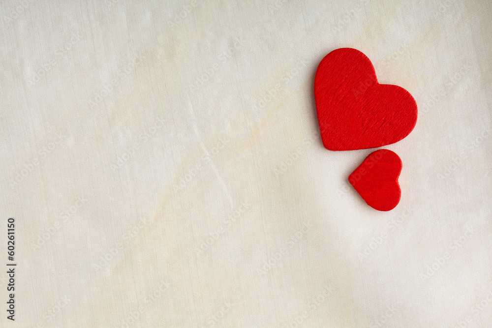 Red wooden decorative hearts on white cloth background.