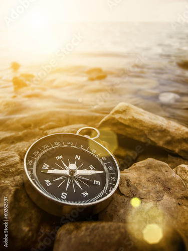 Fotobehang compass on the shore at sunrise