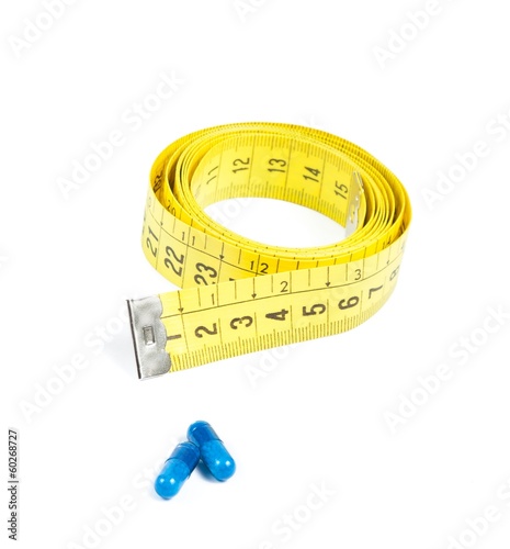 medical blue pills in front of measure tape, concept for diet