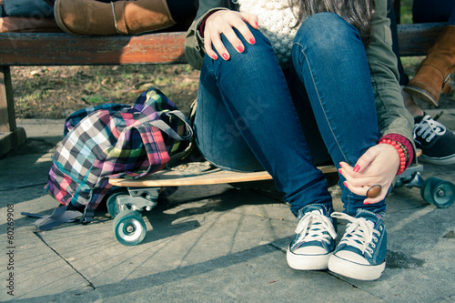Legs of a girl sitting on a skateboard