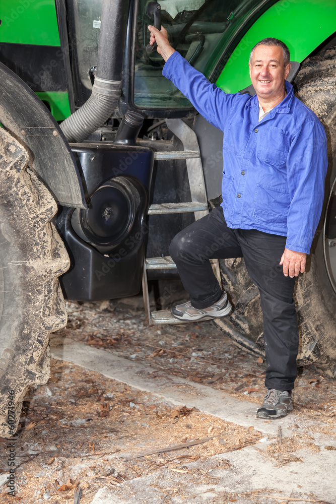 Fototapeta premium Farmer standing in front of his tractor