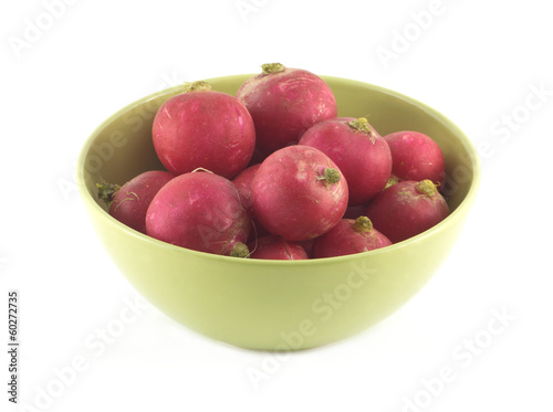 Many red radishes in green bowl isolated close up