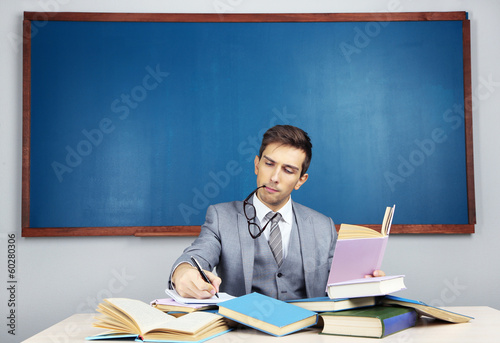 Young teacher sitting in school classroom