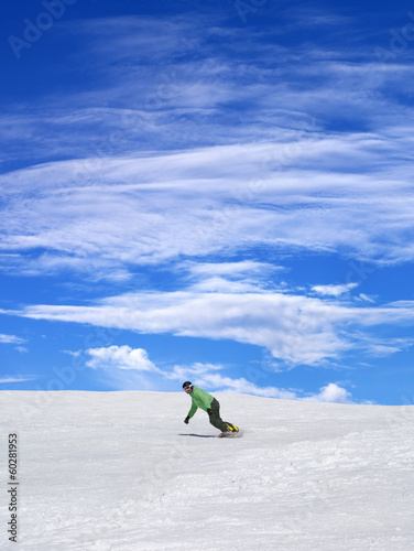 Snowboarder on ski slope and blue sky