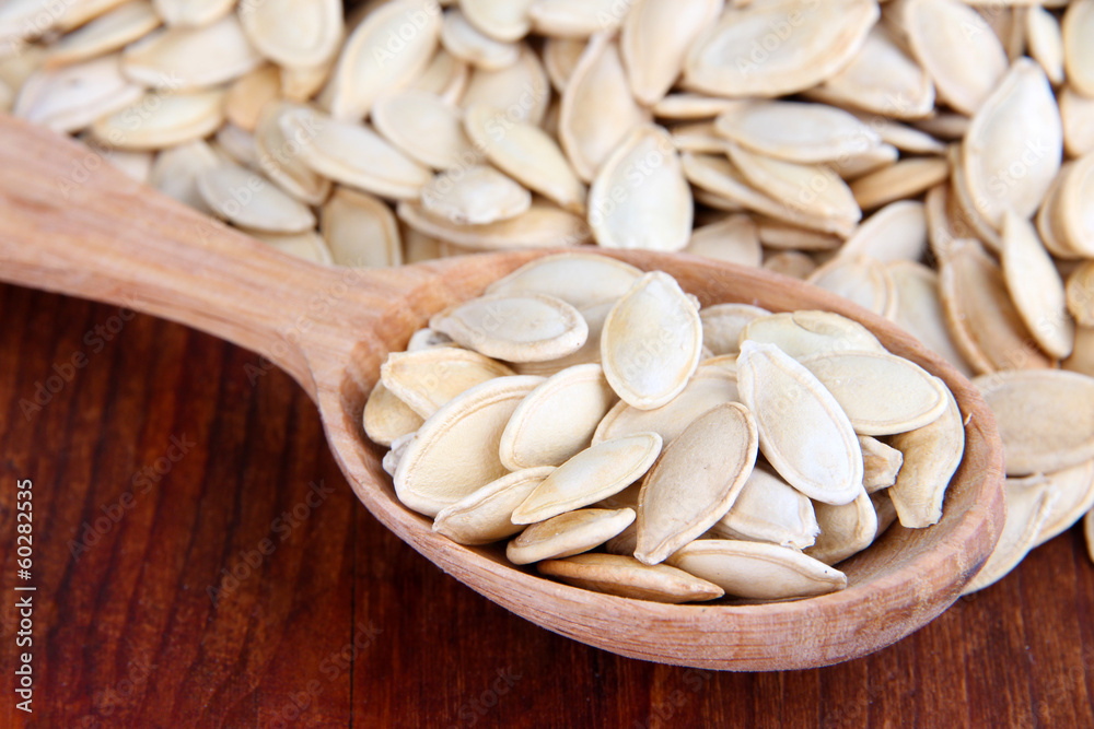 Pumpkin seeds in spoon on table close up Pumpkin seeds in spoon on table close up