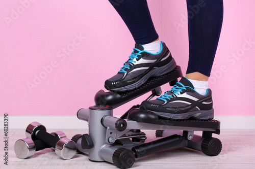 Woman doing exercise on stepper. Close-up on legs. photo