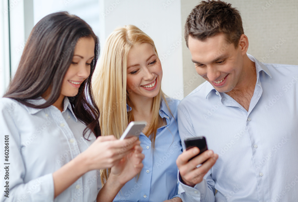 smiling business team with smartphones in office smiling business team with smartphones in office