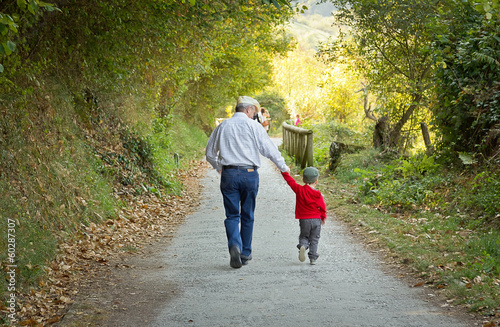 Grandfather and grandchild walking in nature path photo