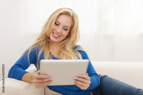 Beautiful blonde woman using digital tablet on sofa