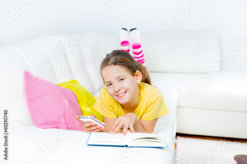  little girl with smart phone and book at home