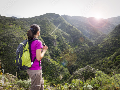 woman hiker with backpack standing on top of a mountain and enjo