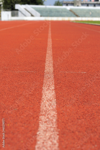 Orange racecourse with white line and grandstand