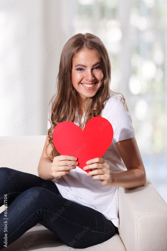 Portrait of a beautiful young woman holding a cardboard heart Portrait of a beautiful young woman holding a cardboard heart