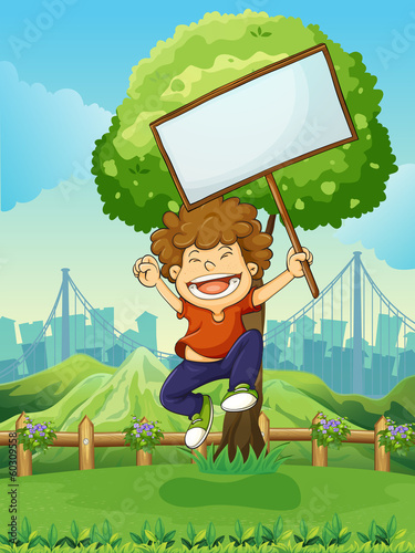 A happy boy jumping while holding an empty signboard