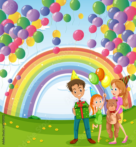 A family below the floating balloons with a rainbow