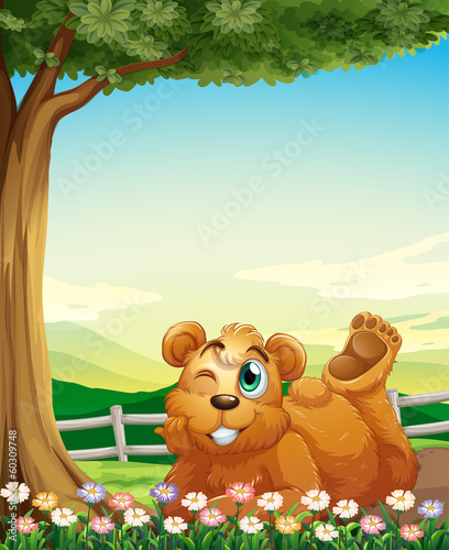 A bear under the tree near the flowers