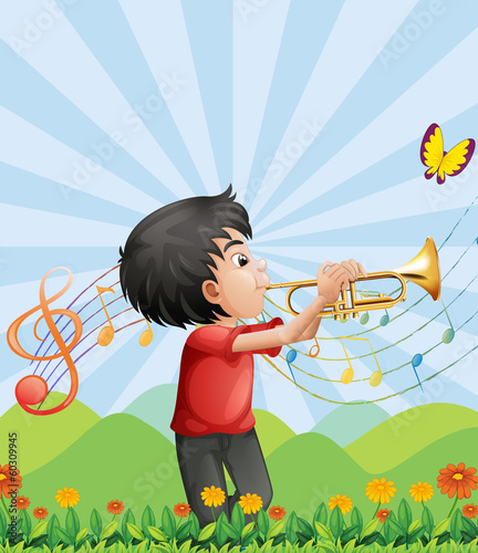 A young man near the hill playing with the trumpet