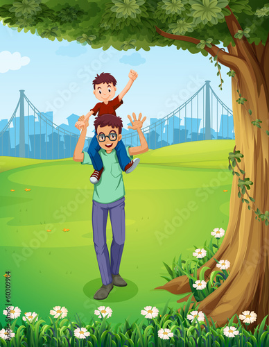 A father carrying his son near the tree across the buildings