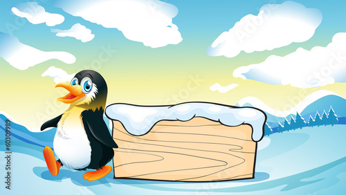 A penguin and an empty wooden template in the snowy area