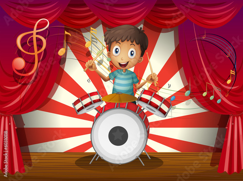 A boy at the center of the stage with a drum