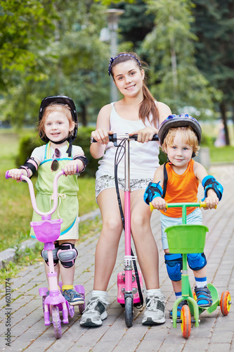 Three smiling children scooterists in summer park photo