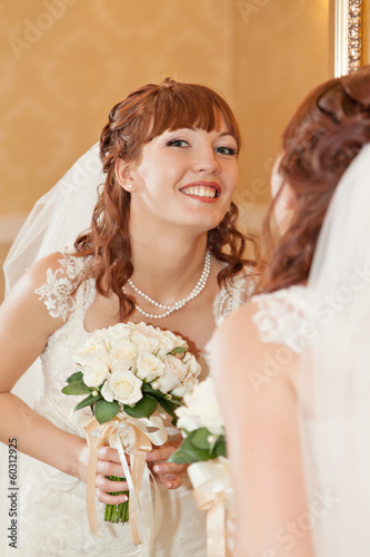 Beautiful bride  looking through mirror and smiling