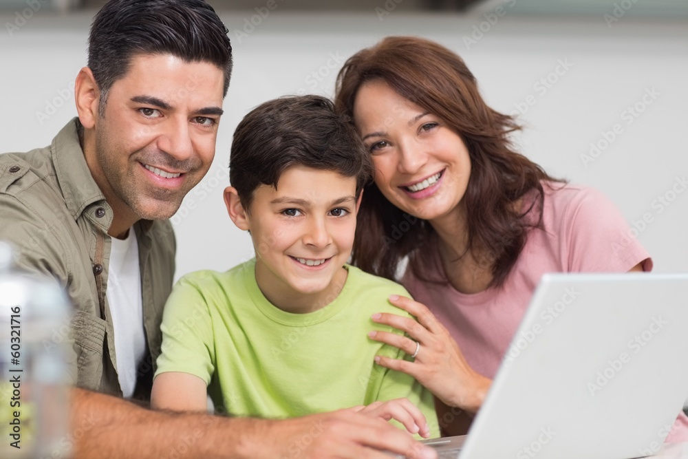 Smiling couple with son using laptop