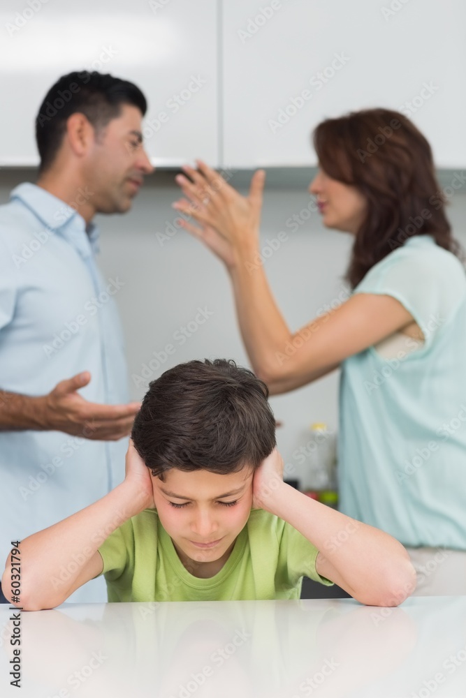 Boy covering ears while parents quarreling in kitchen Boy covering ears while parents quarreling in kitchen