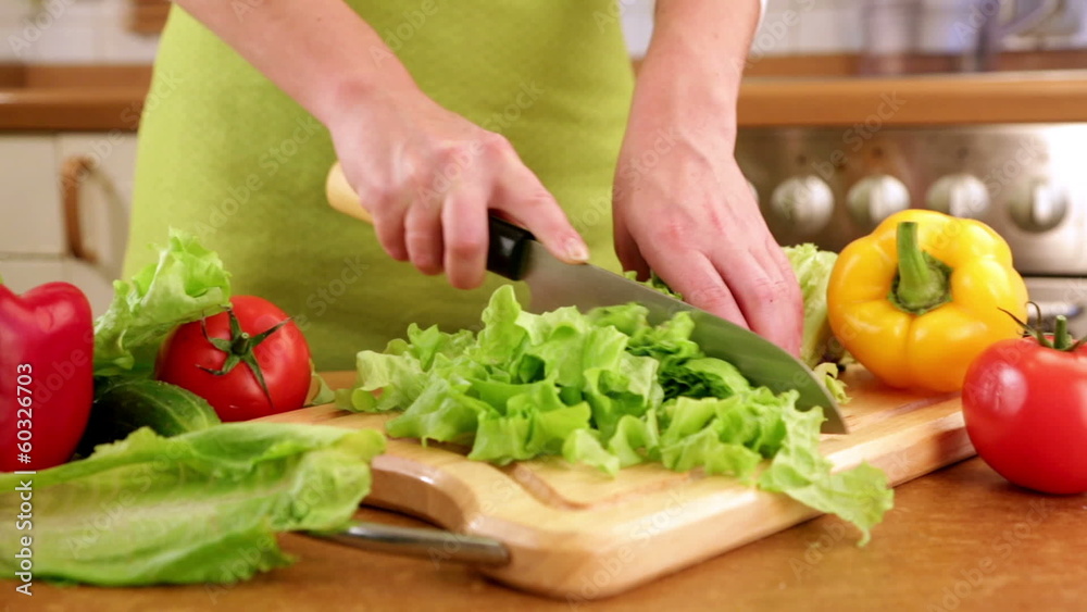 Woman's hands cutting lettuce, behind fresh vegetables. Woman's hands cutting lettuce, behind fresh vegetables.