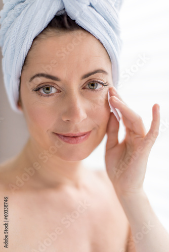 Beautiful mature lady using a cotton pad to clean her skin