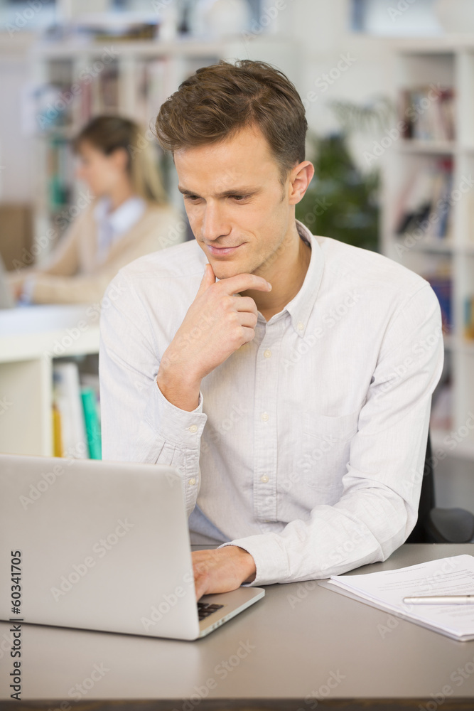 Obraz premium Portrait of smiling businessman working on computer in office